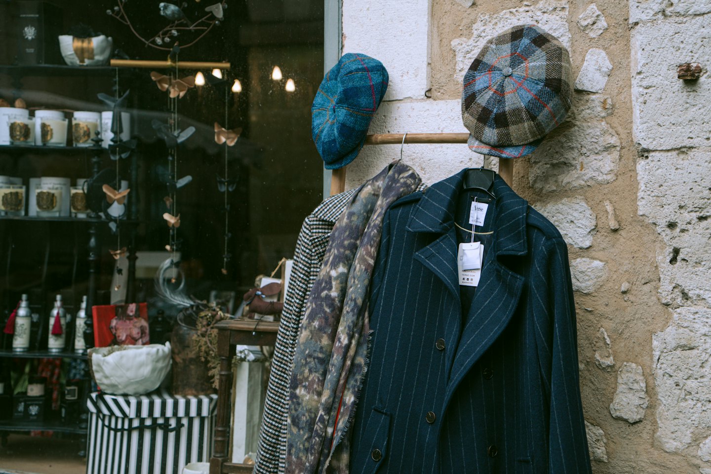 Ropa de invierno colgada en un perchero de madera a las afueras de una boutique.