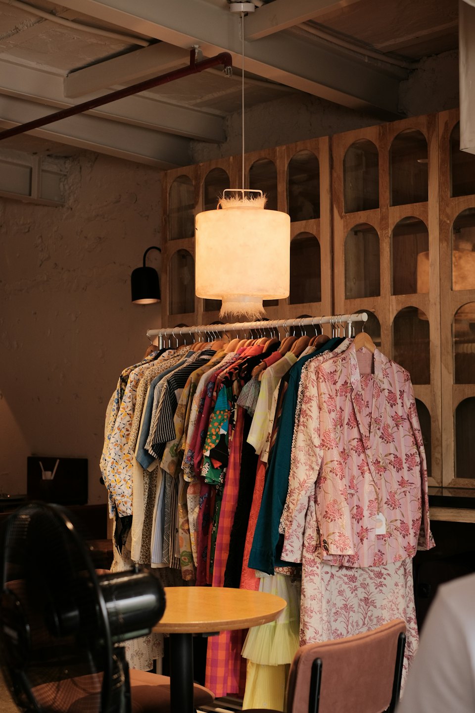 Ropa colorida con estampados cuelga en un perchero dentro de una boutique.
